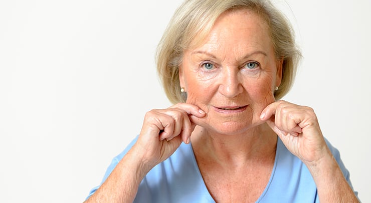 Older woman pinching her saggy jowls.