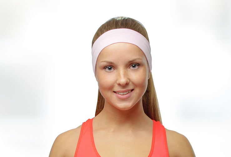 Young woman wearing pink headband after otoplasty.
