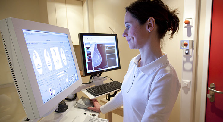 Female mammogram technician examining mammogram report.