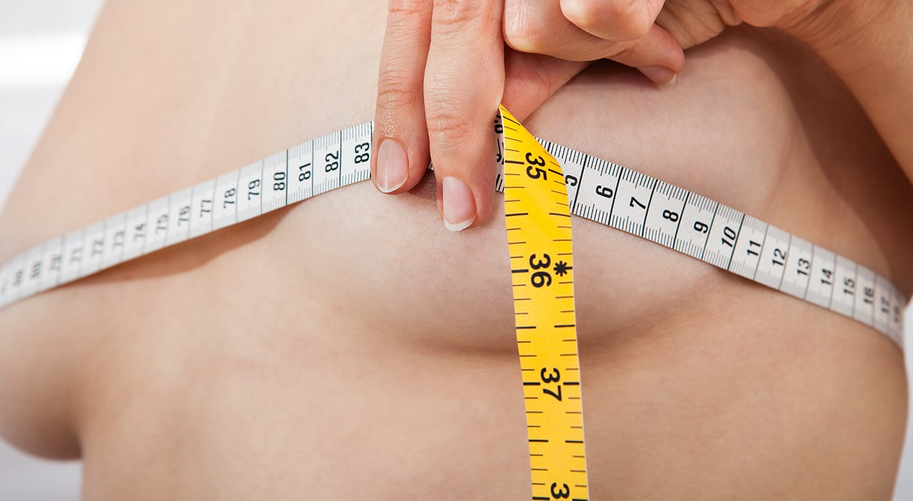 Woman using tape measure to see her breast size for breast augmentation.