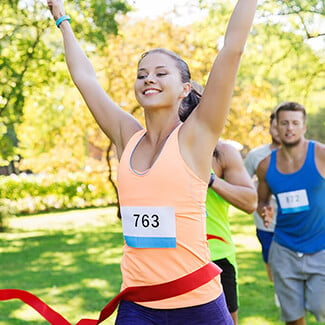 Woman crossing finish line to win a running race.