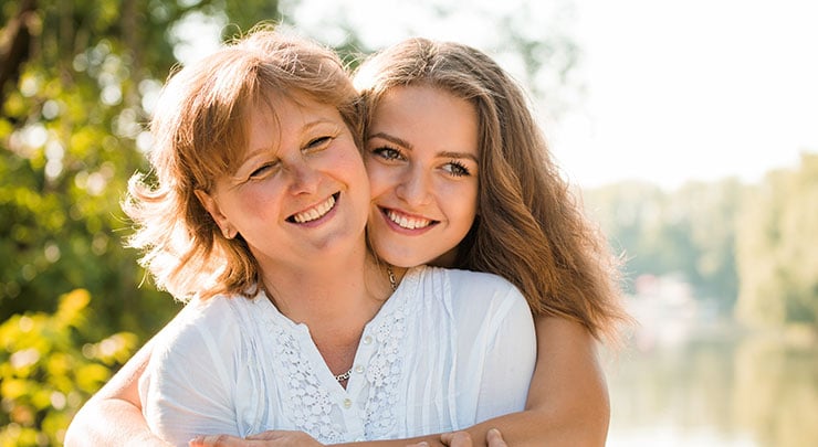 Mother and daughter hugging and smiling after clitoral hood reduction.