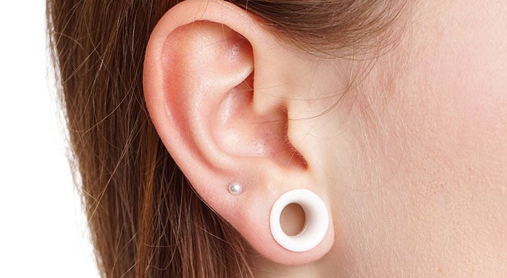Woman's ear with stretched ear piercing gauge.