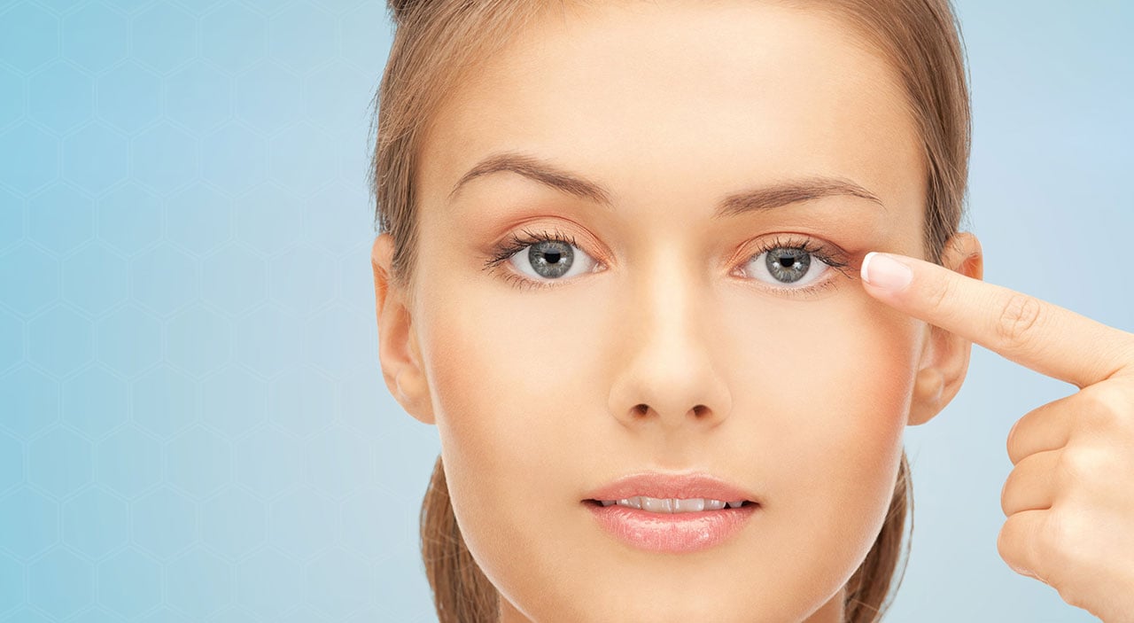 Young woman pointing at one of her eyelids.