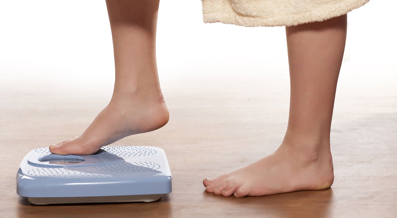 Woman stepping on scale to weigh herself.