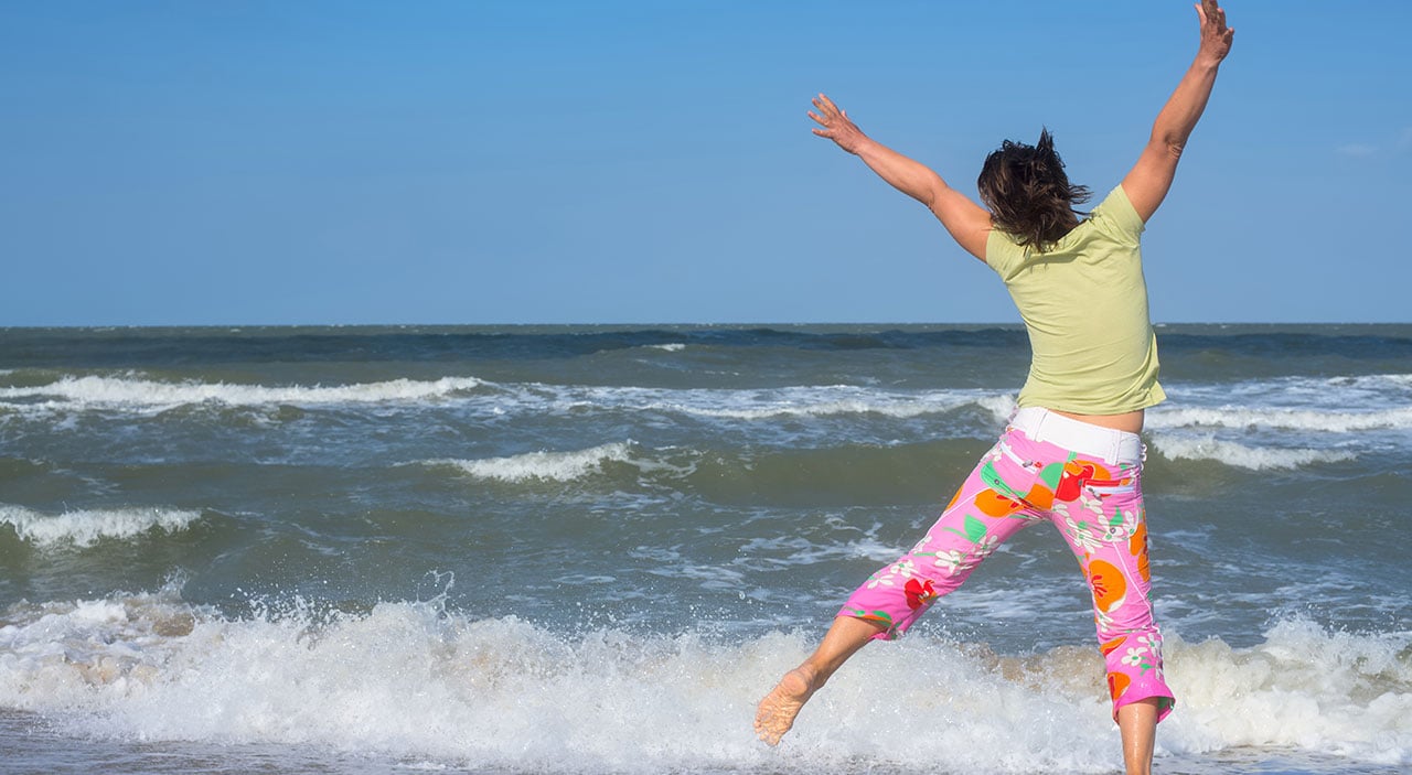 Woman jumping up in happiness at beach.