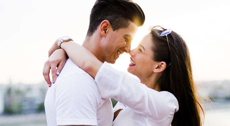 Woman and man hugging and smiling at each other.