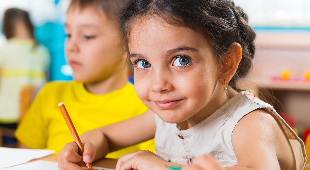 Young girl sitting at desk in school doing homework.