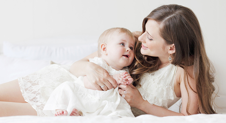 Woman leaning against elbow cuddling with baby.