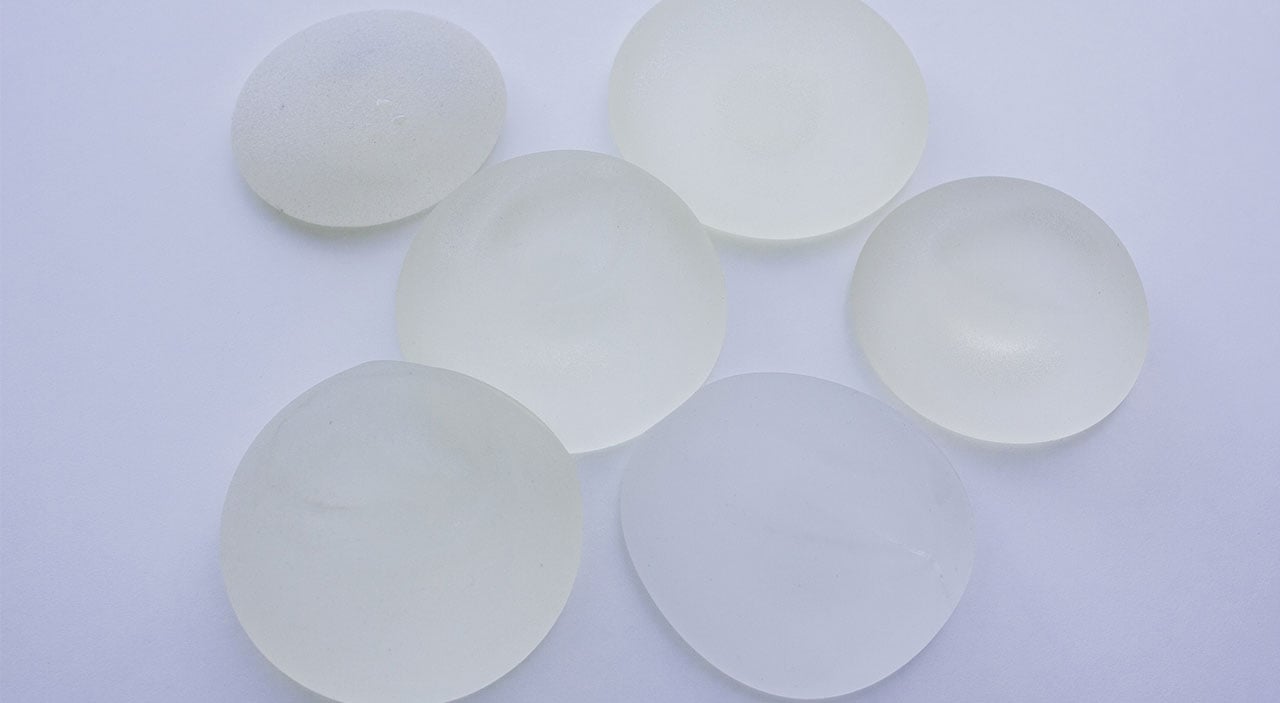 Silicone breast implants lying on grey table.