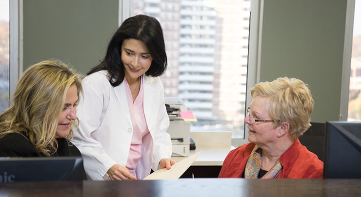 Dr Leila Kasrai speaking with her patient coordinators at the reception desk.