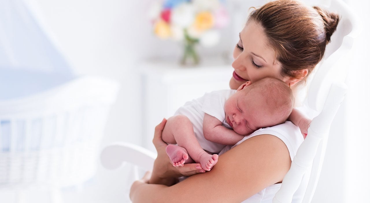 Woman sitting with baby in her arms.