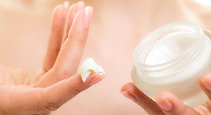 Woman with cream on her finger to apply to tummy tuck scar.