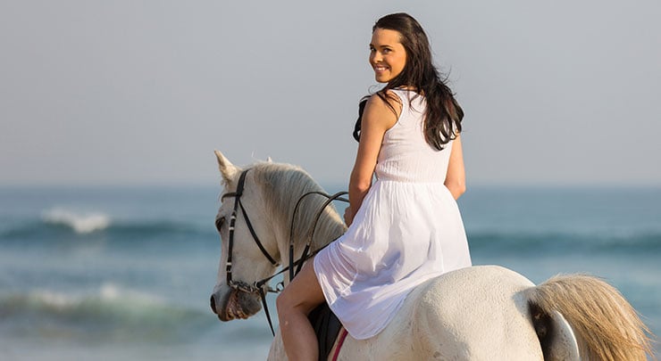 Woman horseback riding on beach after she got labiaplasty.