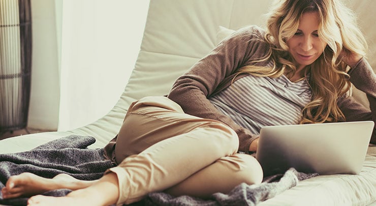 Woman reading a book as she relaxes and recovers after her breast lift.